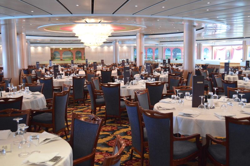 Cruise ship main dining room with round tables set in white linen