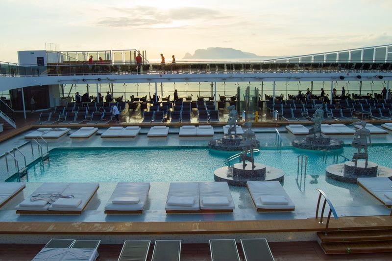Cruise ship pool deck with loungers at dusk, the sea beyond the rail