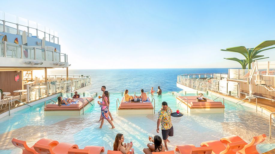 Guests wading in a shallow pool at the stern of a cruise ship with open ocean behind