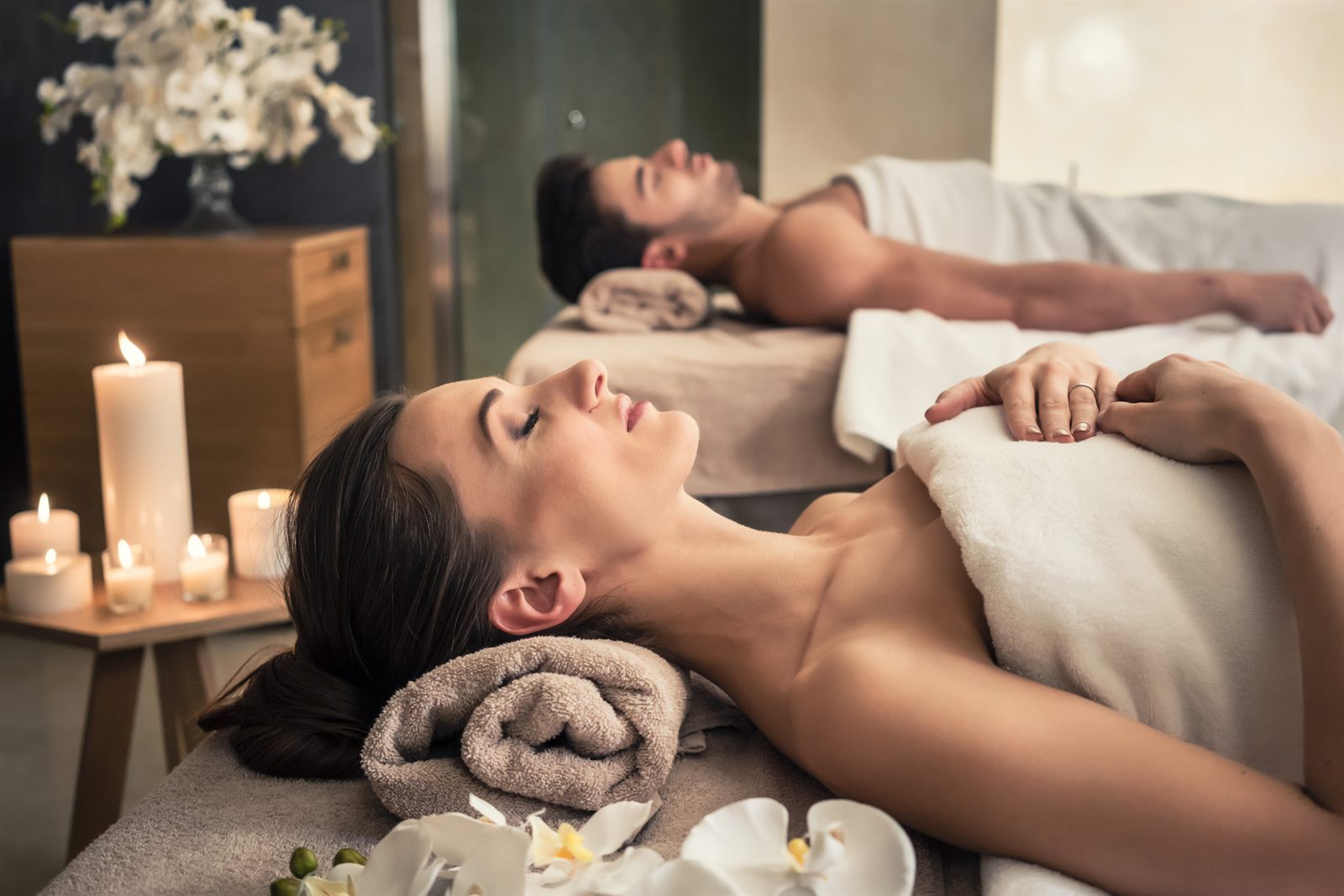 Two guests relaxing on massage tables in a candlelit spa room